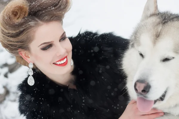 Young woman with wolf dog in snow