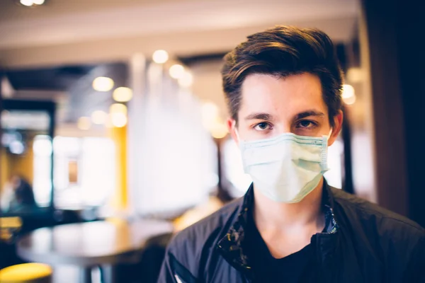 Man wearing medical face mask in the a restaurant. Male wearing face mask, protection from virus infection.