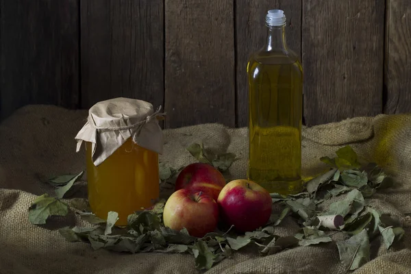 Apples with a jar of honey and a bottle of olive oil