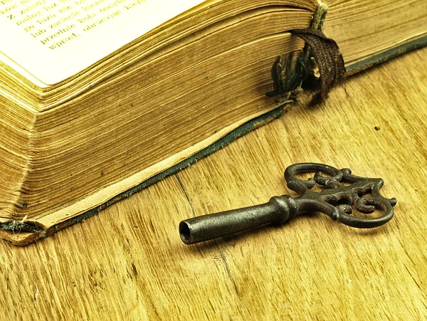 Key and old, open book with a damaged cover.