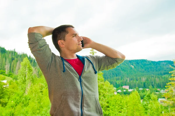 Young man calling on mobile phone. Mountains. Communication conc