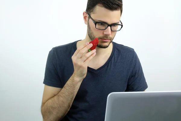 Young man eating a strawberry