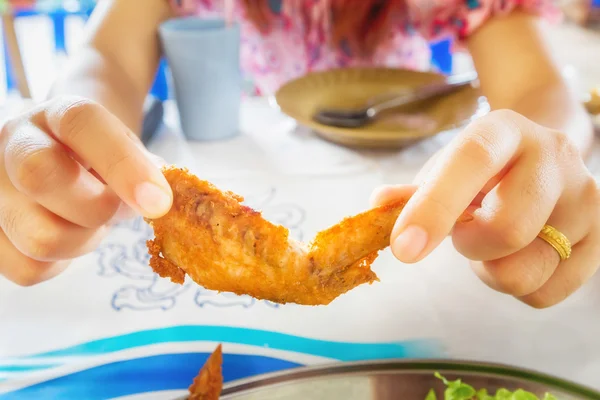 Women eating chicken wings in Thai restaurant.