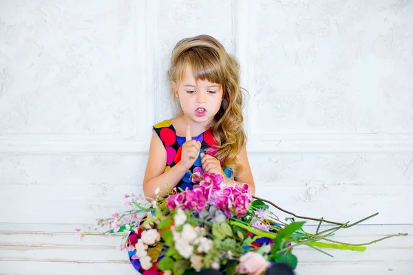 The little girl poses near flowers