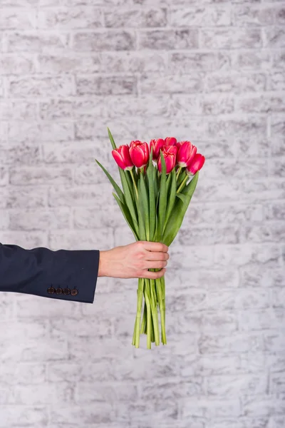 Smiling businessman holding flowers  over white background. Bouq