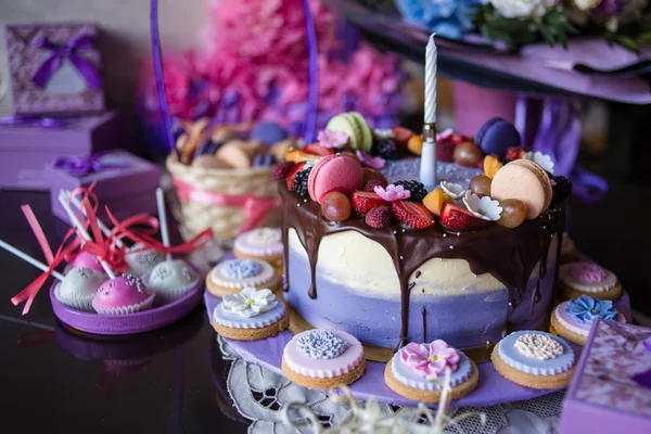 Beautiful purple cake with macaron and biscuits on the table
