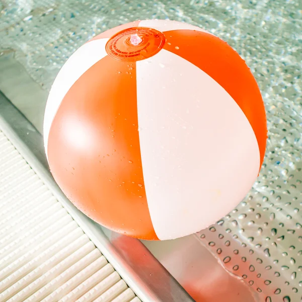 Border of an rustless indoor baby pool with a red and white inflatable ball