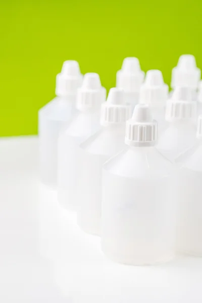 White translucent bottles on green background