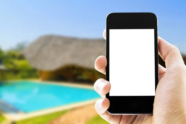 Hand holding phone with blurred swimming pool  background
