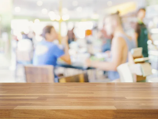 Empty wooden table and blurred people in cafe background