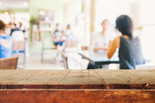 Empty wooden table and blurred people in cafe background