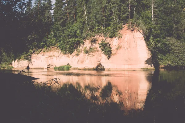 River with reflections in weater and sandstone cliffs. Vintage.