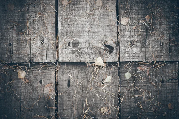 Old wooden planks covered with leaves. Retro grainy film look.