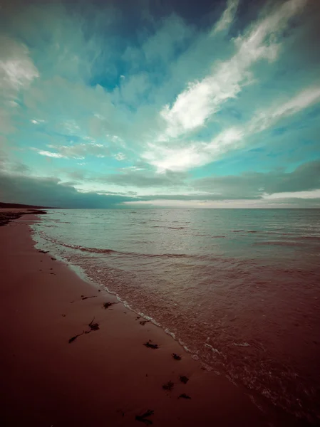 Baltic beach in fall with clouds and waves towards deserted dune