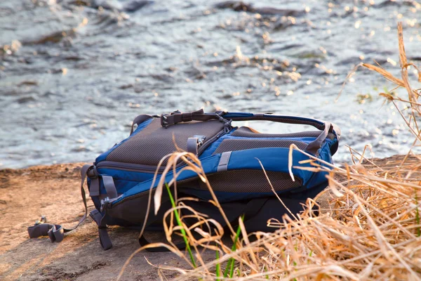 The backpack lies on a stone against water flow