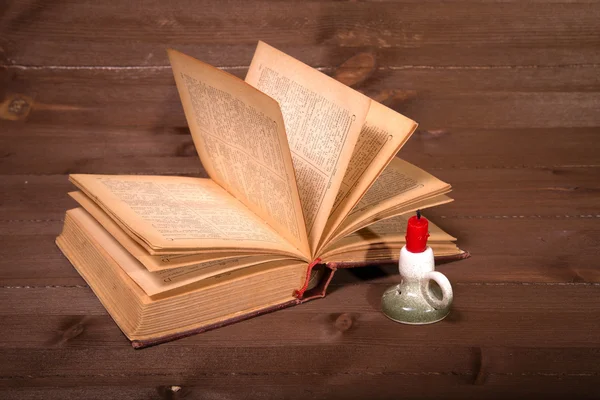 The old book and candle on a wooden table