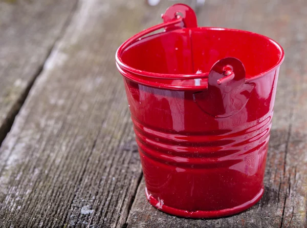 Red brilliant metal bucket on old gray boards