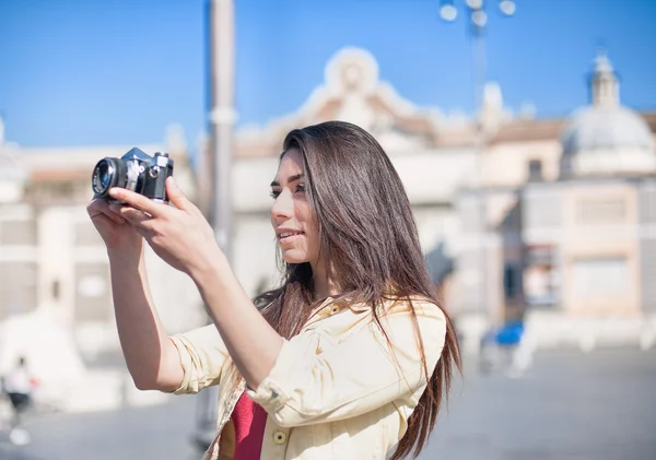Young tourist woman taking picture with vintage camera outdoor