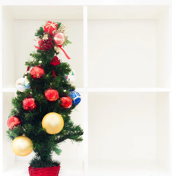Christmas tree on empty white bookshelf