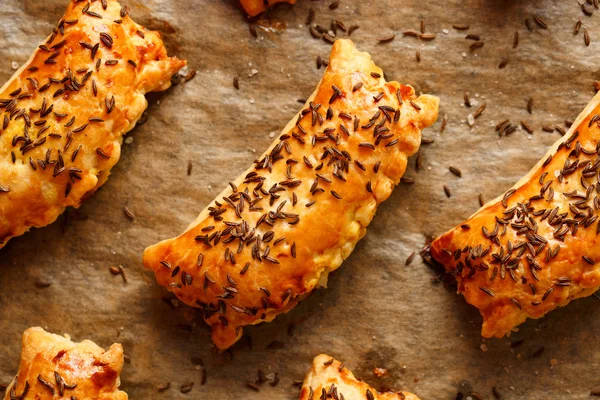 Pasties with puff pastry stuffed with cabbage and mushrooms sprinkled with caraway seeds