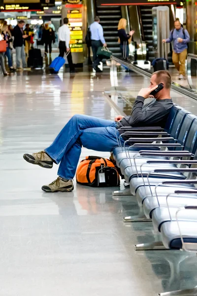 Seated man talking on the phone at an airport