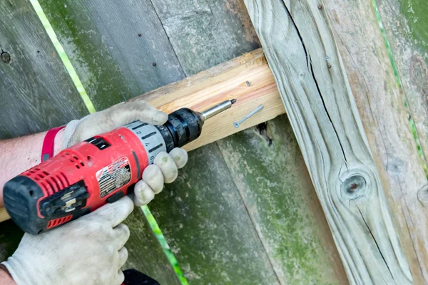 Man drilling holes for wood fence repair