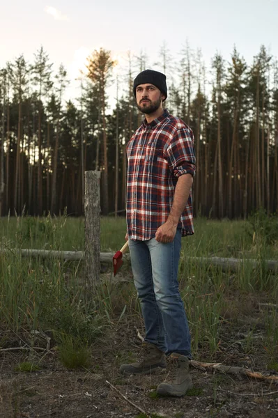 Portrait of bearded Lumberjack with Hat, Boots, Shirt and Ax