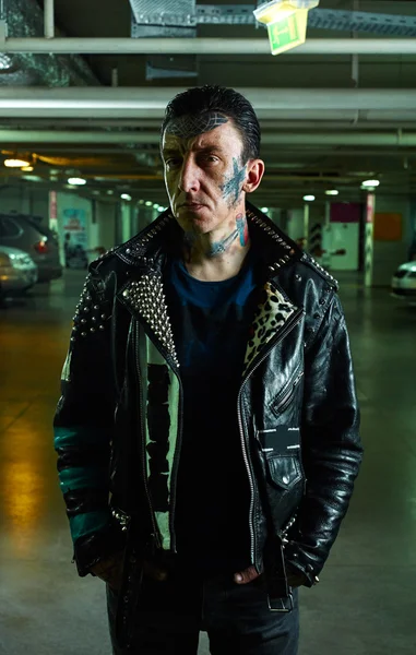 A Man with tattooed Face in leather Jacket on Parking
