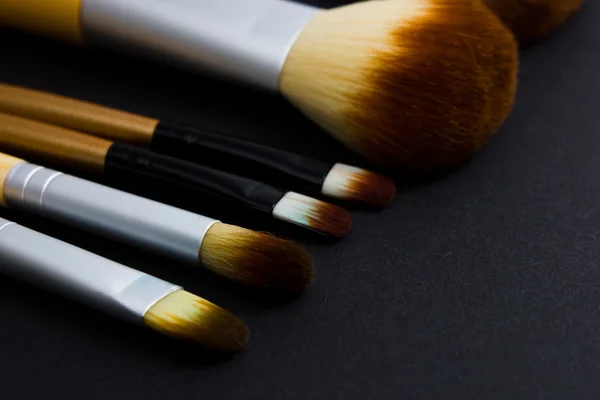 A set of brushes for professional makeup on a black background.