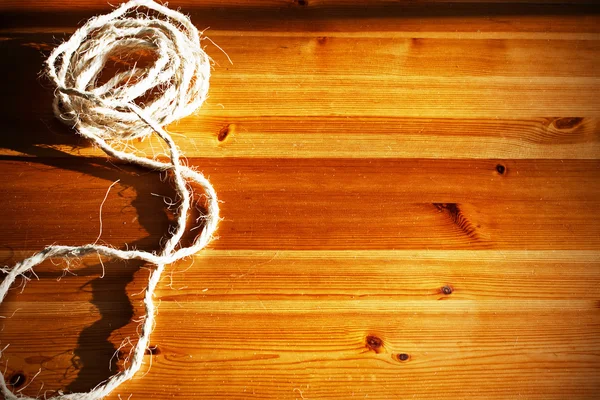 Vintage toned image of hank large ship\'s rope on the background of a brown wooden table.