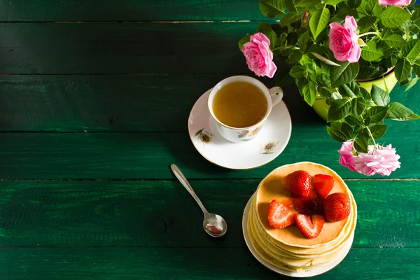 Traditional breakfast: pancakes with syrup and strawberry, green