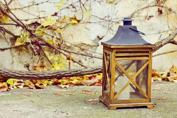 Old wooden lamp with a candle in autumn garden