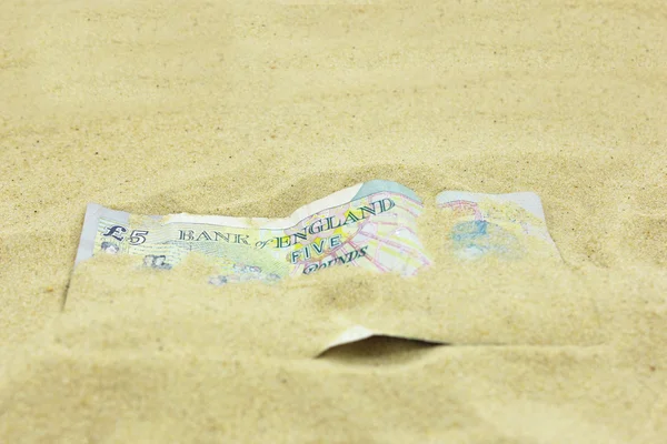 British Five Pound note covered in sand