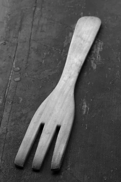 Wooden kitchen fork on an old black table close-up, selective focus. Rustic style. black & white photo. shallow depth of field