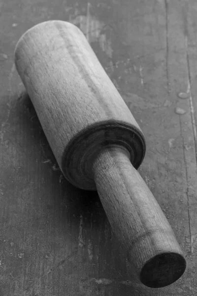 Wooden kitchen pestle on the old black table closeup selective focus. rustic style. black and white photo. shallow depth of field