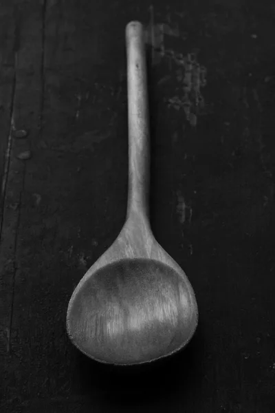 Wooden kitchen spoon on an old black table, closeup, selective focus. rustic style. black and white photo. shallow depth of field