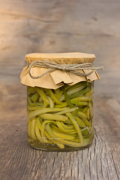 Pickled garlic sprouts in glass jar closeup. home canning
