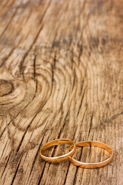 Male and female wedding rings of gold on an old cracked wooden board. selective focus. Free space for text. Copy space