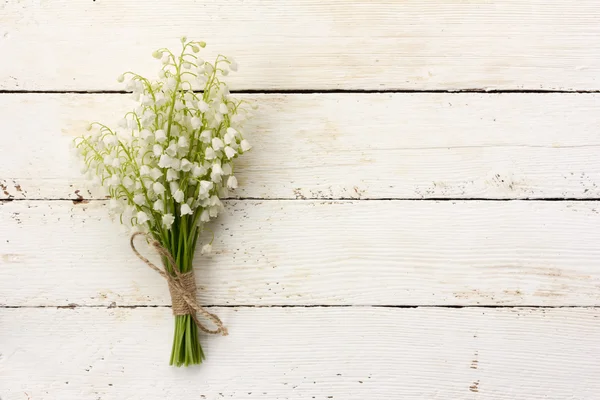Lily of the valley bouquet of white flowers tied with string on a white background barn boards. with space for posting information