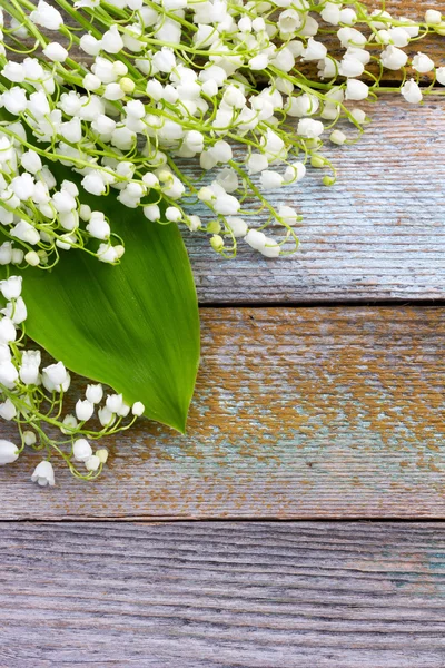 White flowers lilies of the valley scattered on the old wooden background. with space for text