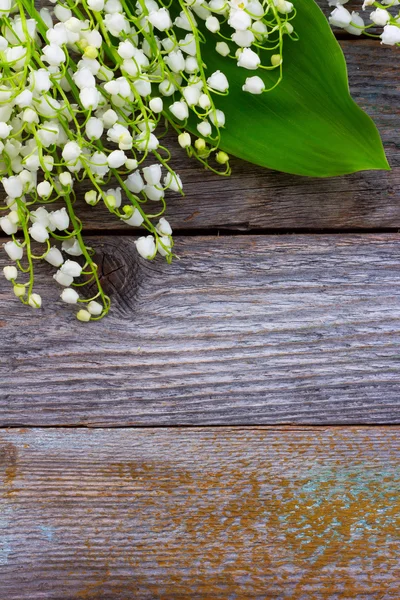 White flowers lilies of the valley scattered on the old wooden background. with space for text