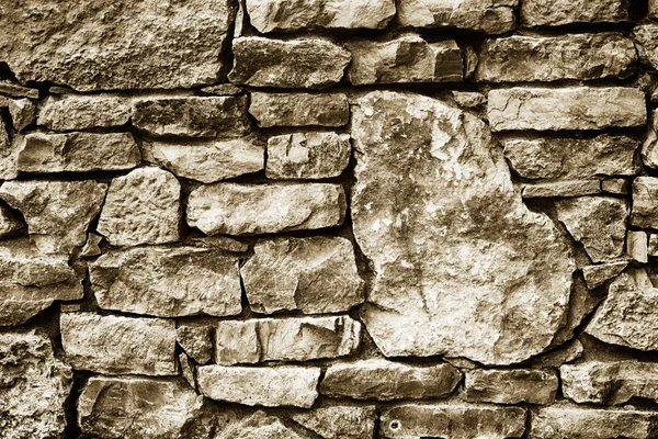 Black and white texture background of a wall lined with natural stone close-up, toned photo