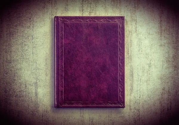 Purple book on a grey grunge background, top view. tinted photo with vignetting, retro toned image