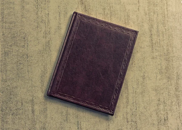 The book is dark purple on a grey grunge background, top view. tinted photo, retro toned image