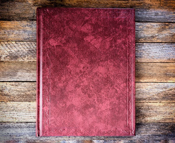The book is red on the old wooden boards close up, top view. tinted photo, retro toned image