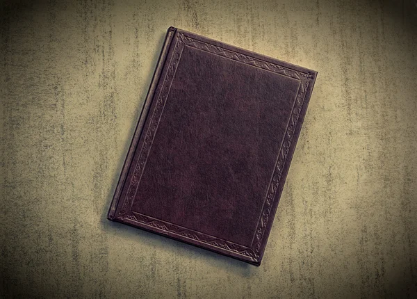 The book is dark purple on a grey grunge background, top view. tinted photo with vignetting, retro toned image