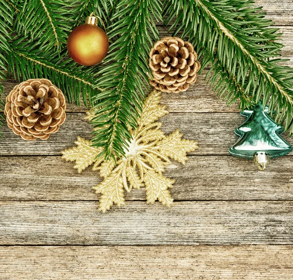 New Year or Christmas background: fir branches, colorful glass balls and golden snow-flake, cones over old wooden backdrop, top view, copy space, tinted photo