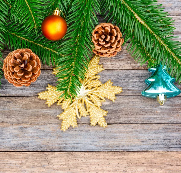 New Year or Christmas background: fir branches, colorful glass balls and golden snow-flake, cones over old wooden backdrop, top view, copy space