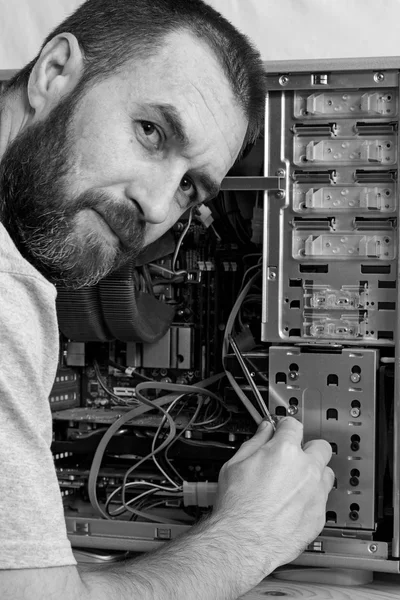 Fixing computer. a man with a beard repair the system unit. black and white photo