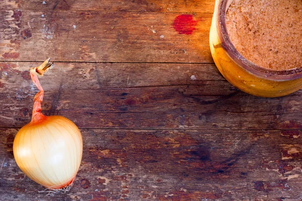 Head goldish onions and a jar of salt on the table made from barn boards. Copy space. Top view. Rustic style